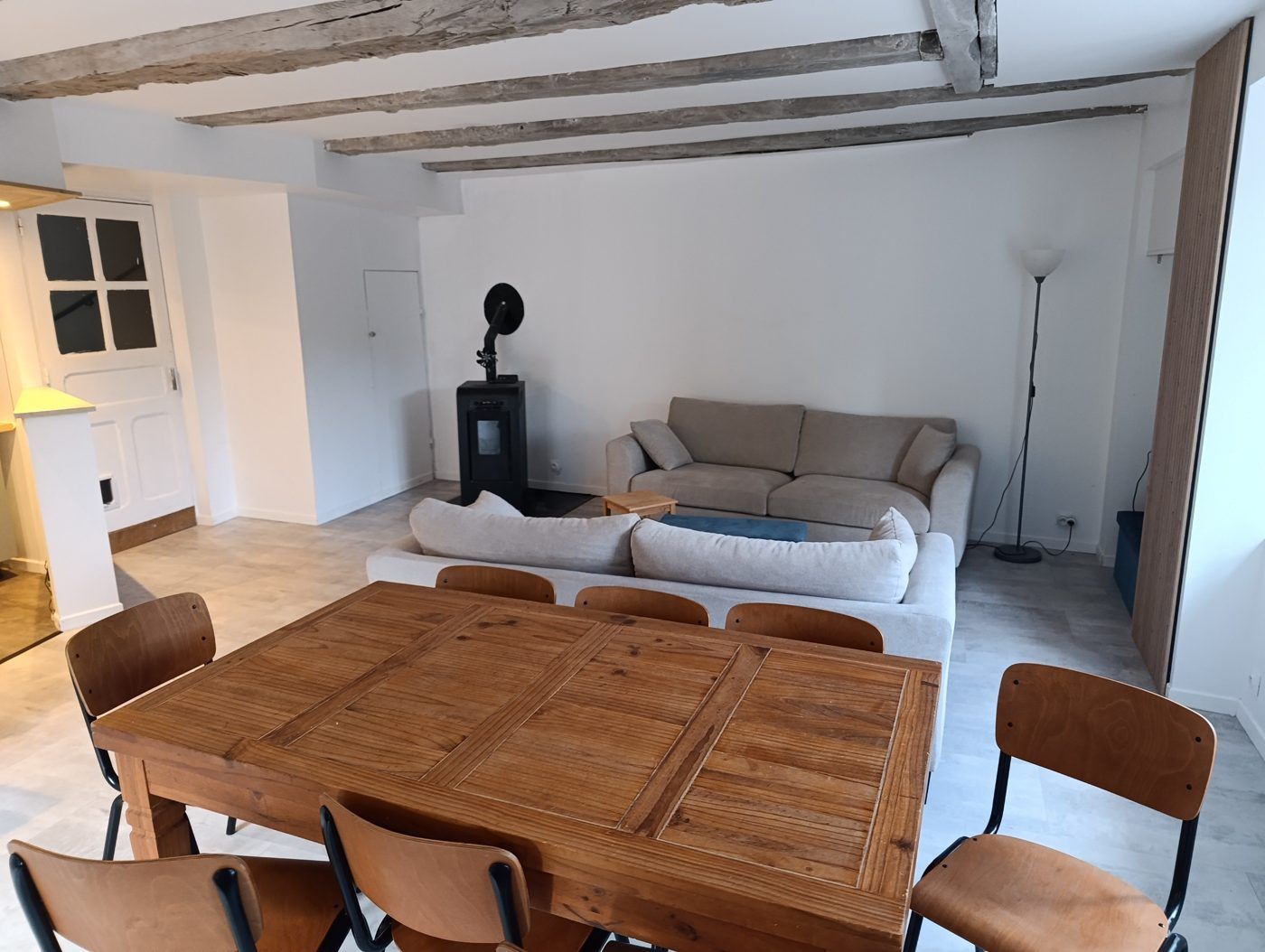 Pièce à vivre avec poêle, canapés et table de repas