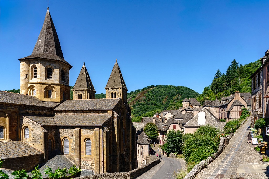 Le village médiéval de Conques-en-Rouergue et son abbatiale Sainte-Foy entourés de collines verdoyantes en Aveyron